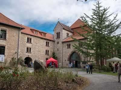 Das Bild zeigt einen Innenhof des Klosters Brunshausen mit ein paar Menschen im Vordergrund. 