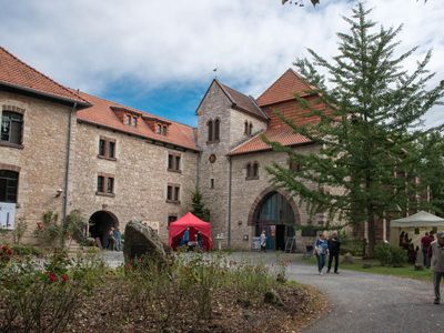 Das Bild zeigt einen Innenhof des Klosters Brunshausen mit ein paar Menschen im Vordergrund. 