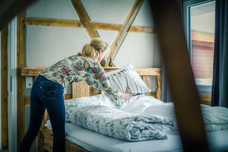 Frau macht ein Bett frisch