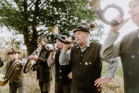 Jagdhornbläser in Tracht spielen beim Schierker Kuhball im Freien.
